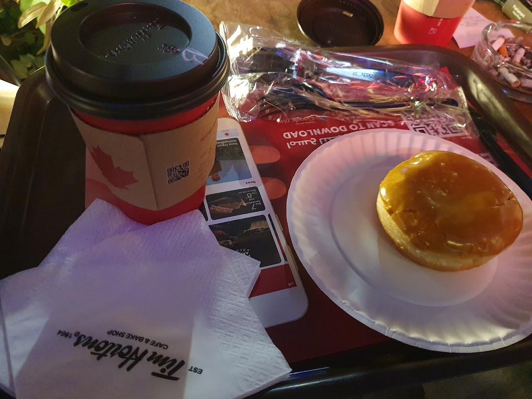 A Tim Hortons coffee cup and a glazed donut on a tray with napkins.