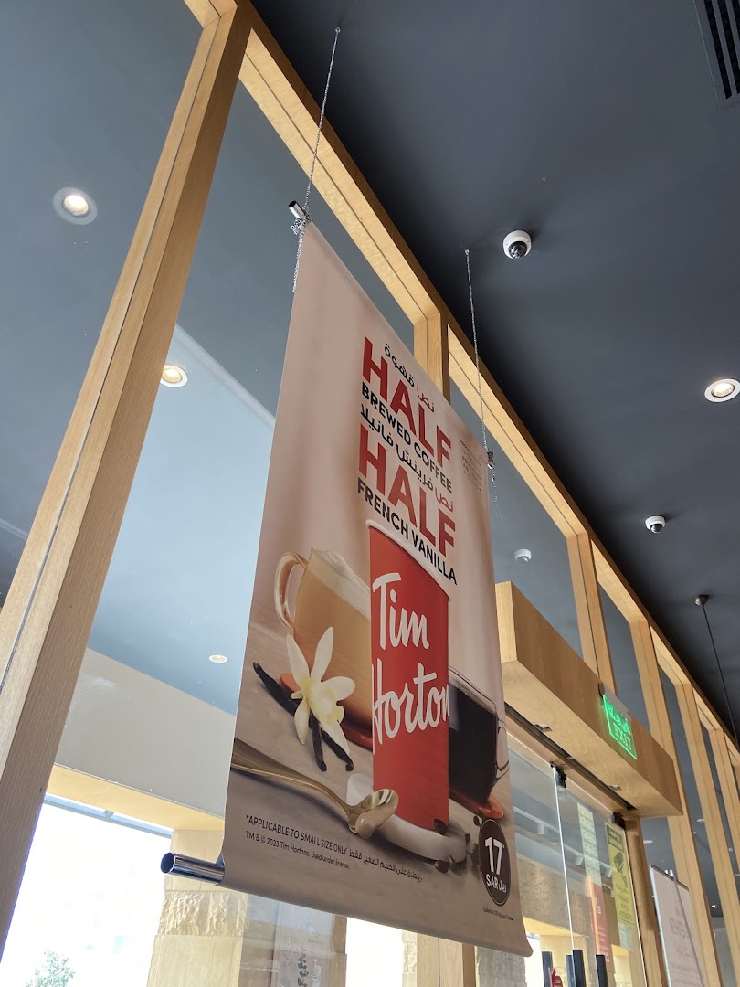 A hanging banner advertises Tim Hortons' Half French Vanilla brewed coffee.