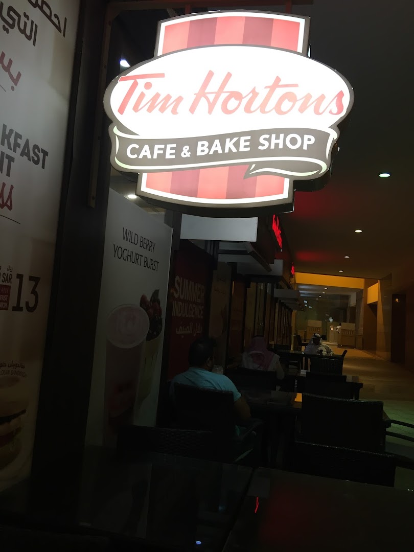 Tim Hortons cafe and bake shop exterior with illuminated signage and seating area.