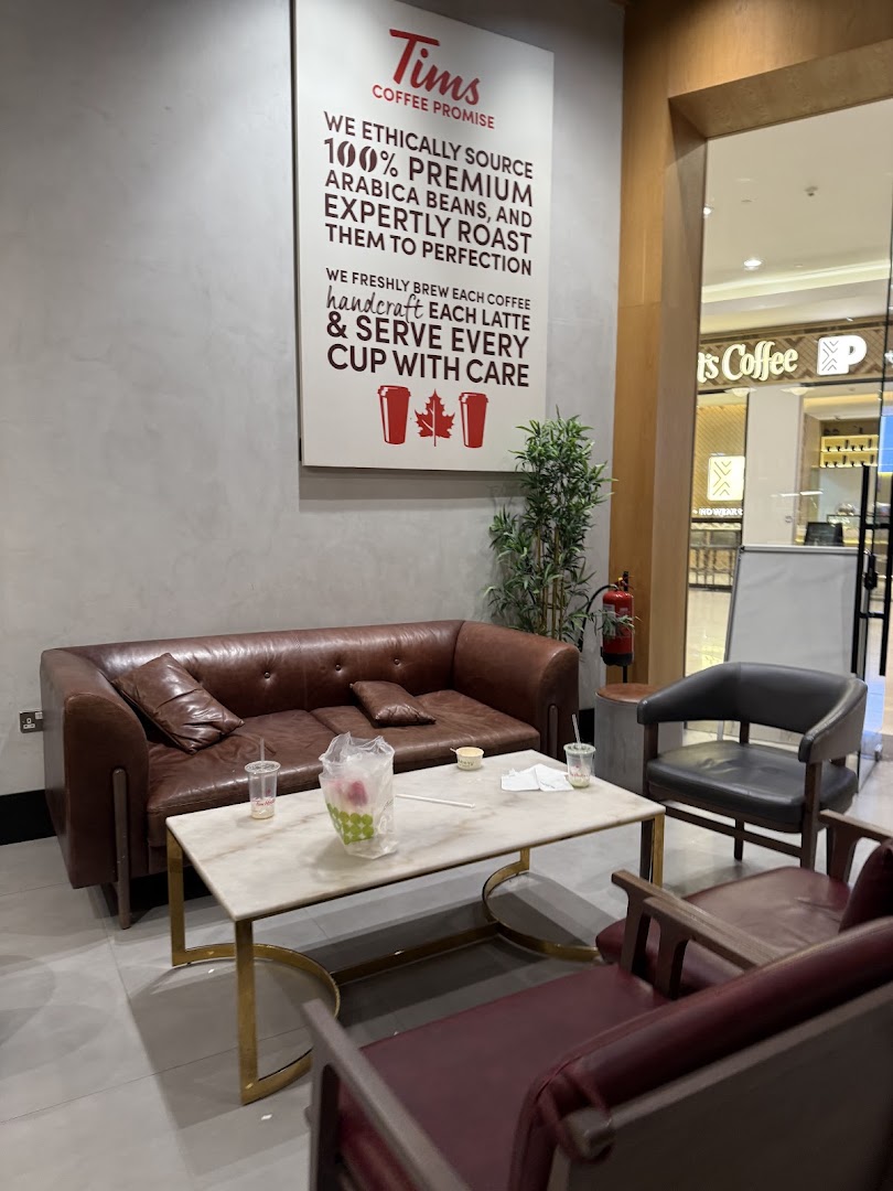 A seating area at Tim Hortons with a coffee promise sign and comfortable seating.