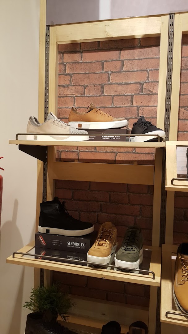 Timberland shoes displayed on shelves with a brick-patterned background.