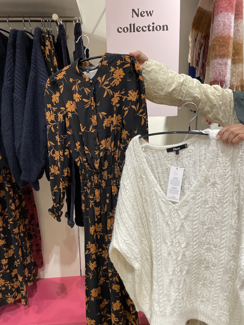 Hands holding a floral dress and a white knitted sweater with a 'New collection' sign.
