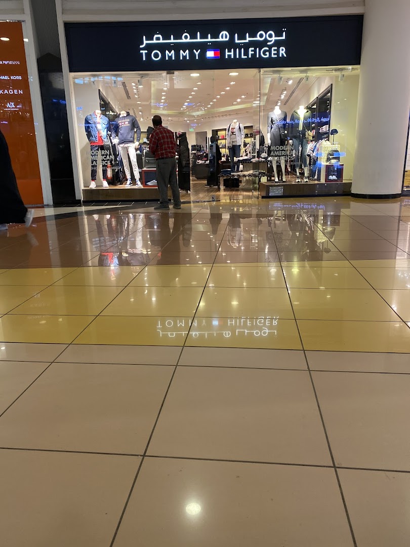 The Tommy Hilfiger store entrance with mannequins displaying clothing and a customer looking inside.
