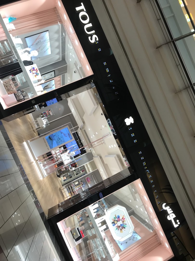 The exterior of a TOUS jewelry store with illuminated signage and display windows.