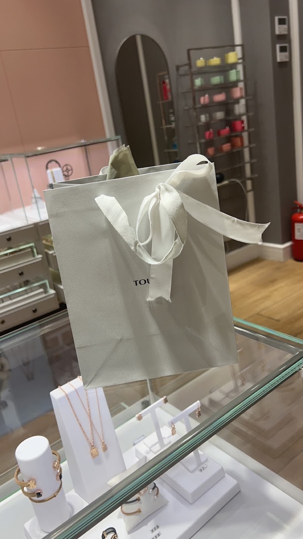 A shopping bag from Tous with jewelry displayed in a display case.