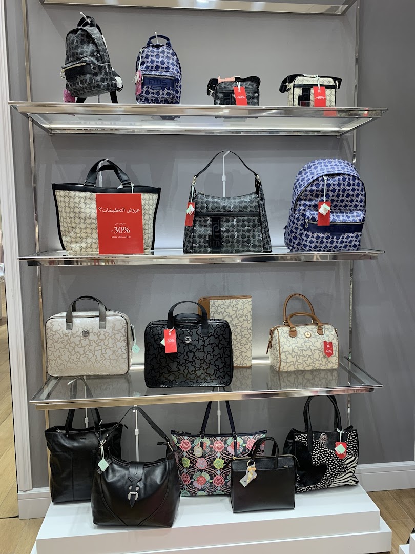 A display of various stylish handbags and backpacks on shelves in a retail store.