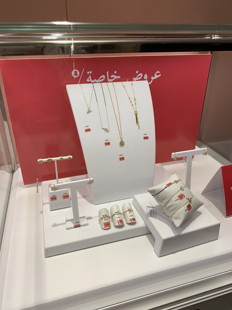 A display of gold necklaces, bracelets, and earrings with price tags in a jewelry store.