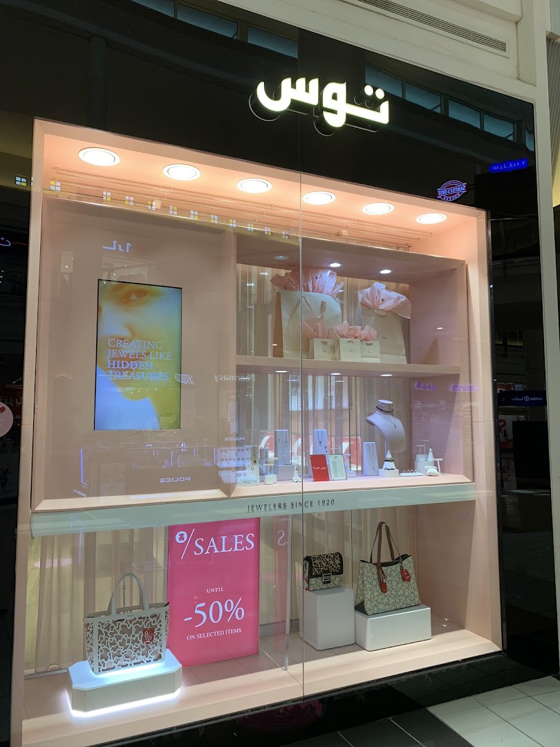 A jewelry store window display featuring handbags, jewelry, and a sale sign.