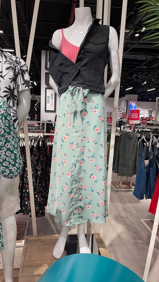 Mannequin wearing a floral skirt and denim vest, showcasing fashion trends.