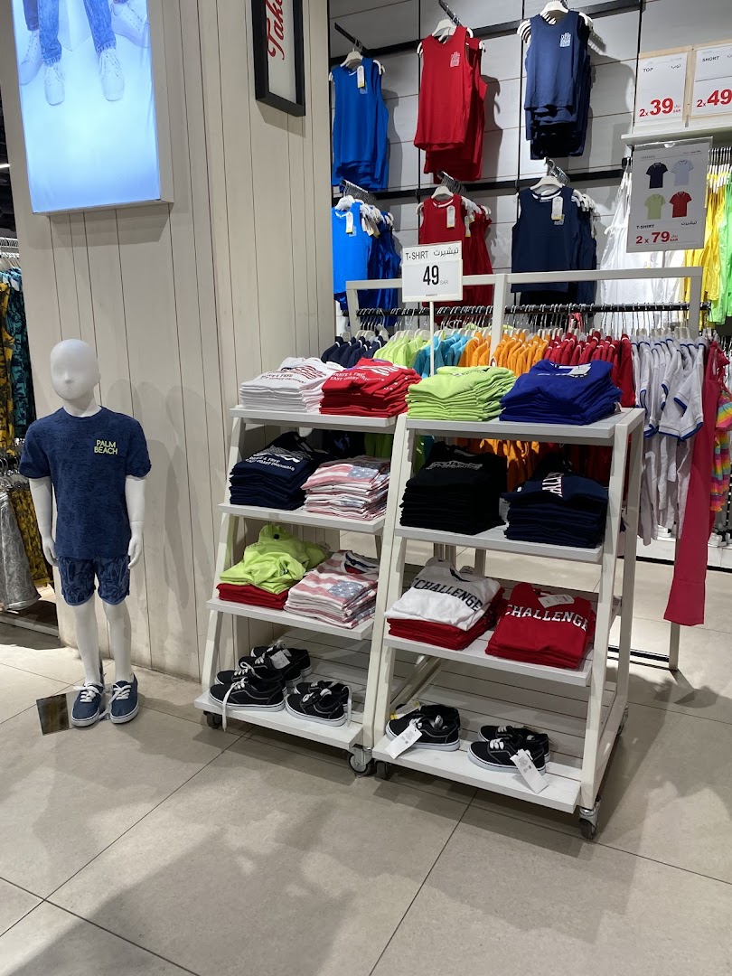 A retail store display featuring folded t-shirts, tank tops, and sneakers for sale.