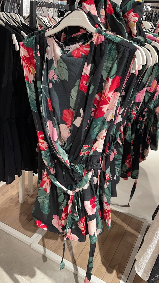 A close-up shot of a floral print dress on a hanger in a clothing store.