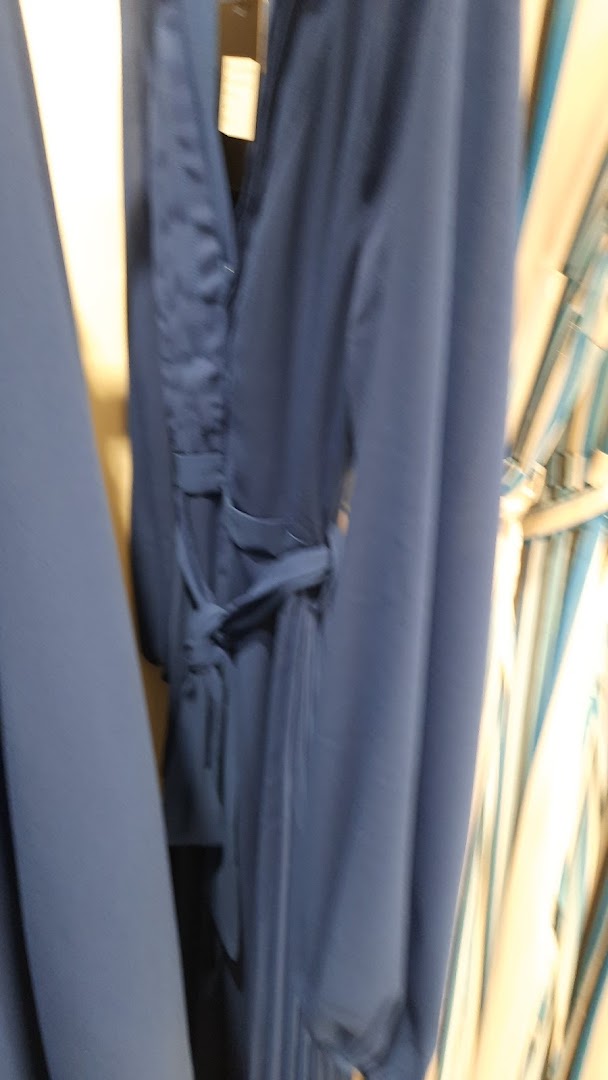 A close-up shot of a navy blue dress with a tie waist, displayed in a store.