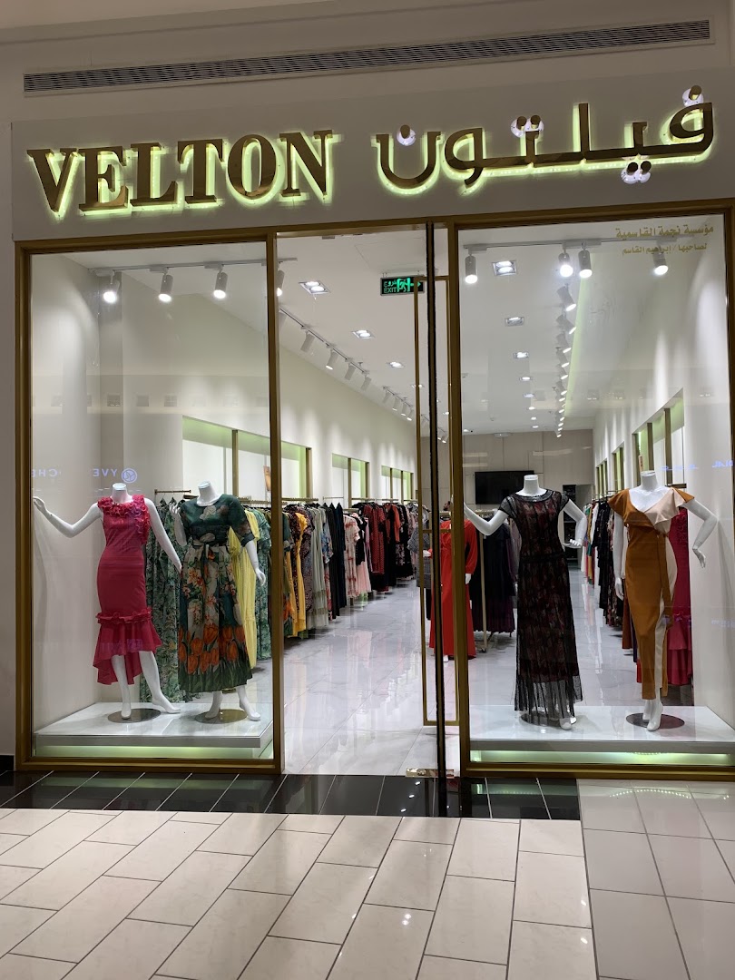 The storefront of Velton, a fashion boutique, showcasing mannequins in dresses and racks of clothing.
