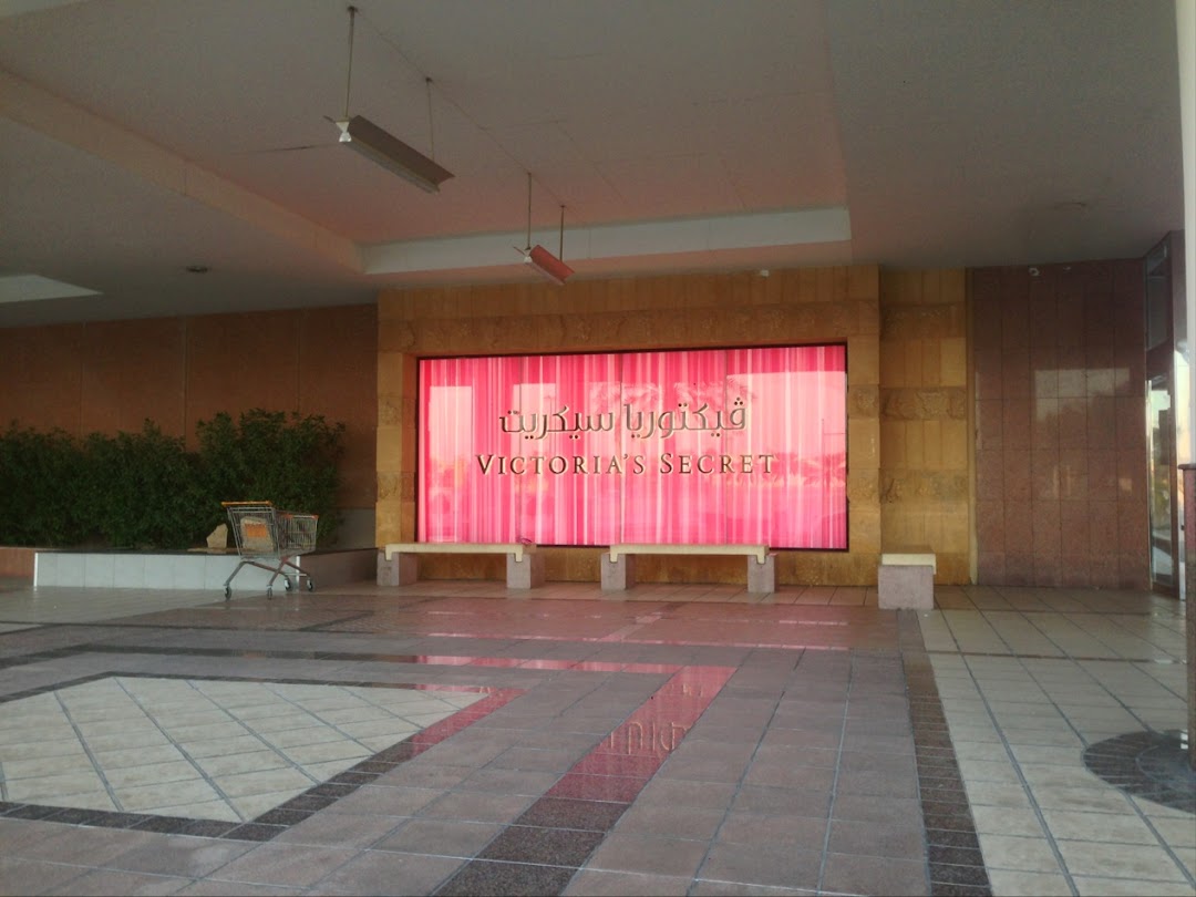 The entrance to Victoria's Secret with a large pink display screen and benches.