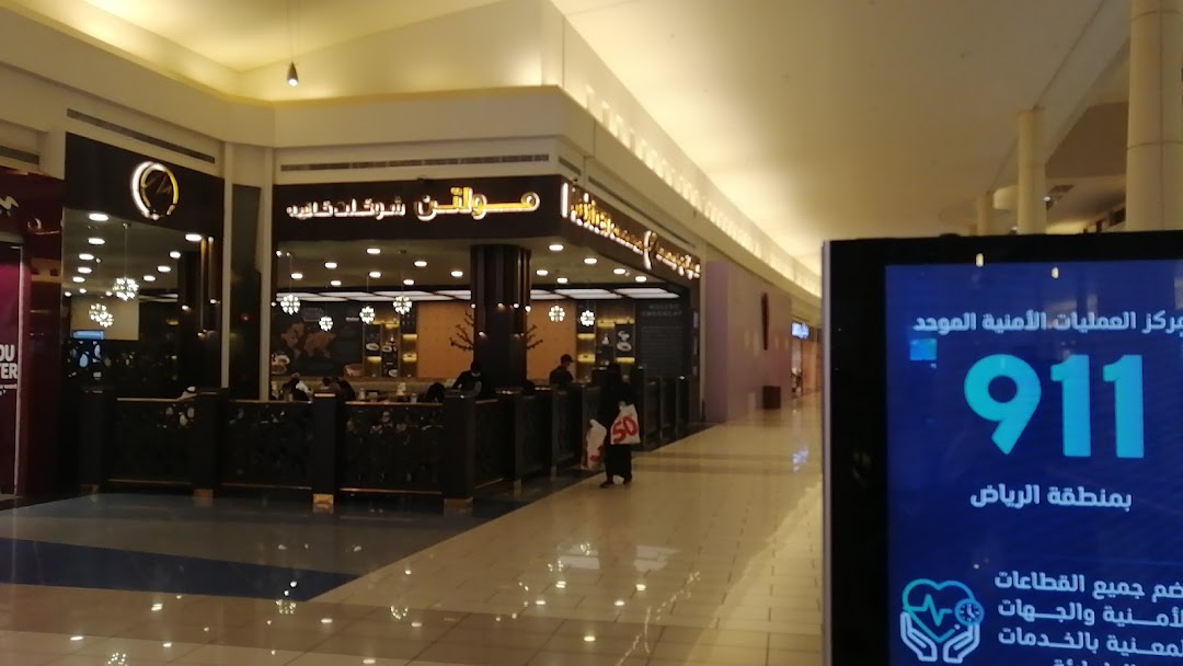 A view of a shopping mall corridor with a cafe and a digital display.