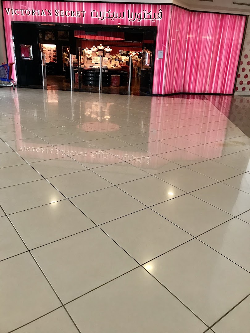 The entrance of a Victoria's Secret store with pink striped decor and mannequins displaying lingerie.