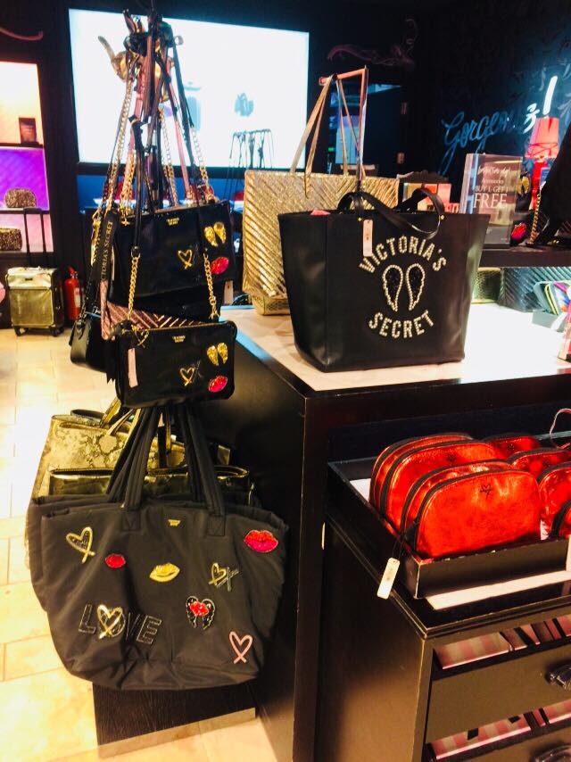 Victoria's Secret shop interior displaying various handbags and cosmetic bags.