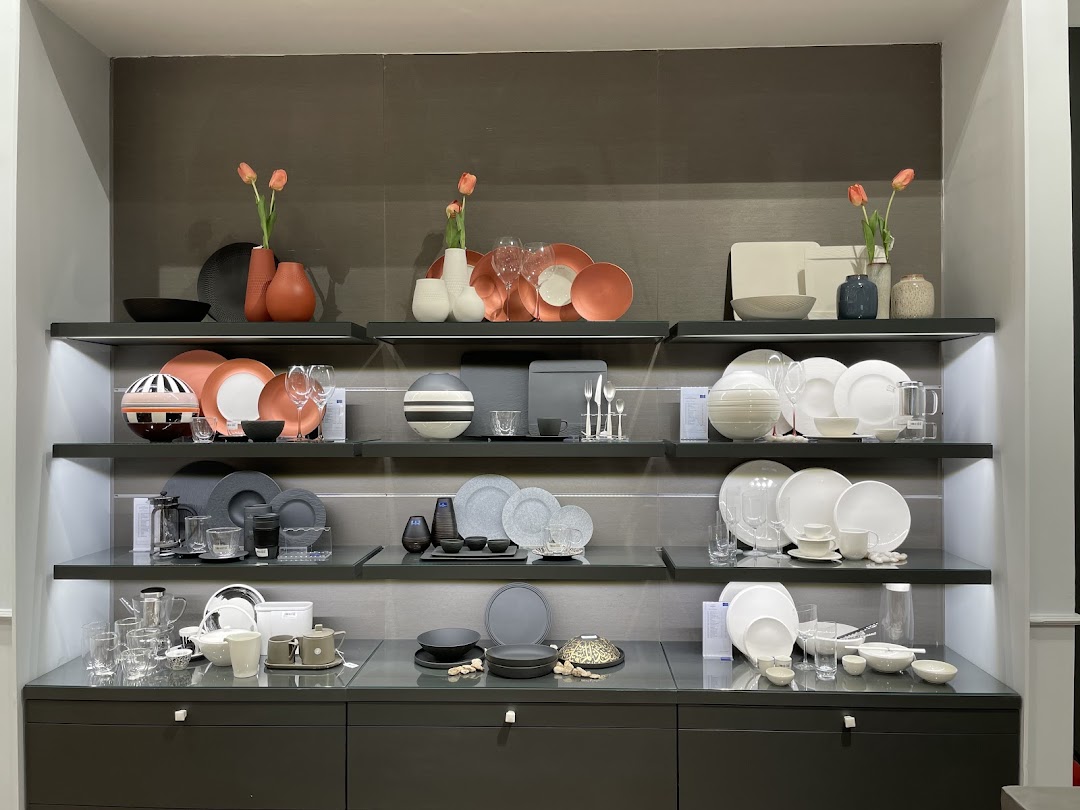 Shelves display a variety of Villeroy & Boch tableware, glassware, and decorative vases.