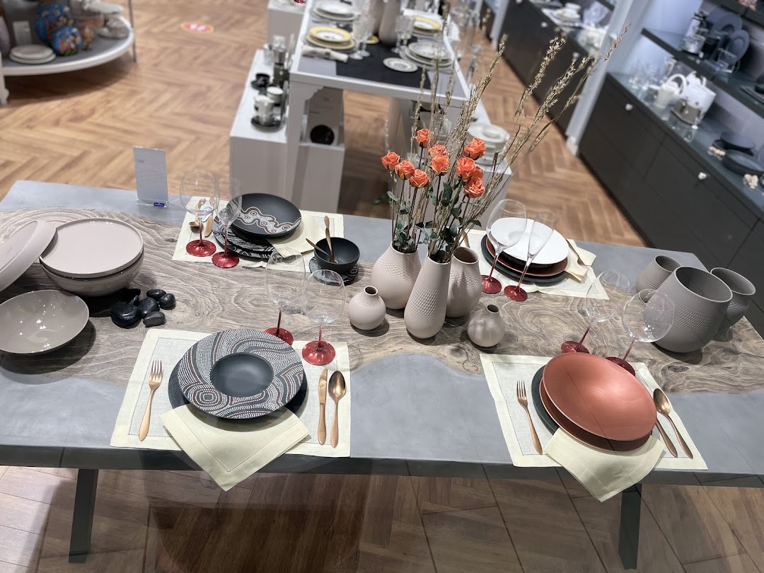 A beautifully set dining table with elegant tableware, vases, and flowers.