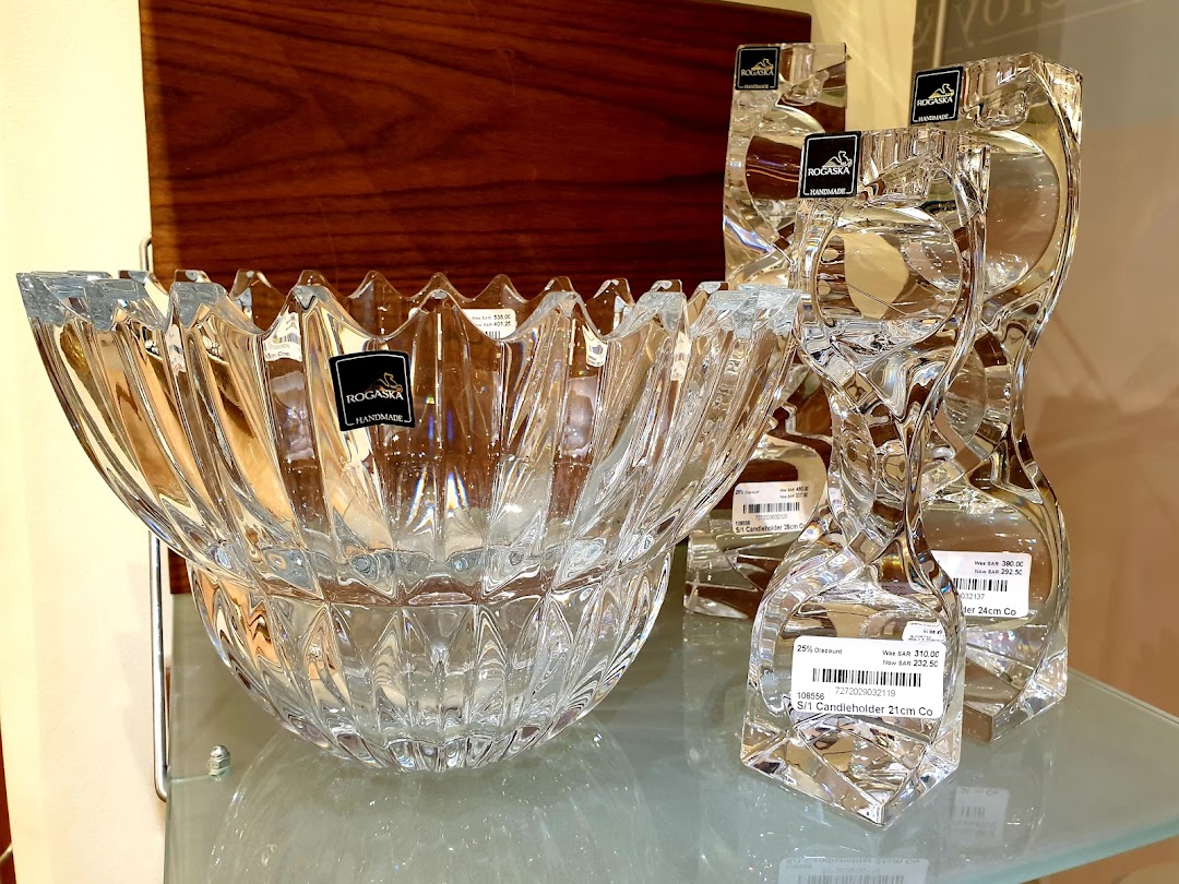 A crystal bowl and two crystal candleholders displayed on a glass shelf.