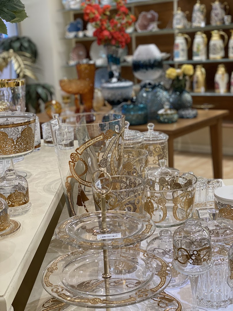 A display of elegant glassware with gold accents, including tiered serving stands and decorative jars.