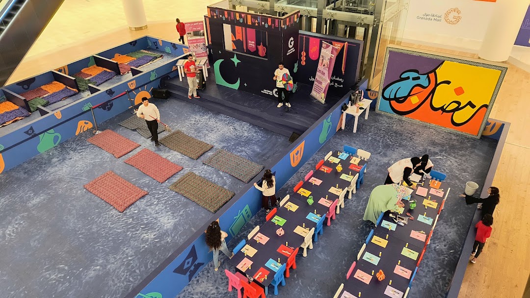 An indoor event space with a stage, seating areas, and activity tables for children.