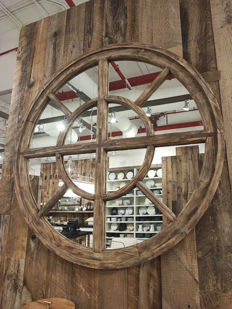 A rustic wooden circular mirror reflects shelves stocked with dishes and kitchenware.