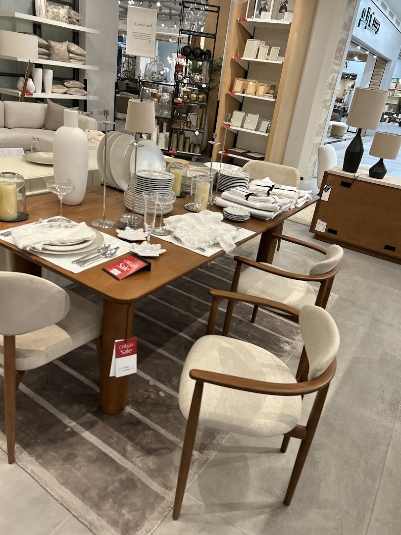 A dining table set with chairs, tableware, and decor in a West Elm store.