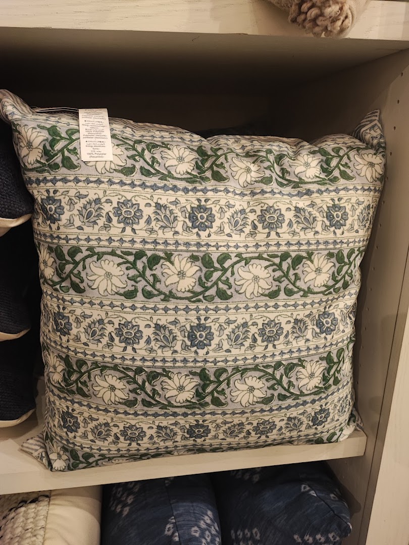 A decorative pillow with a blue and green floral pattern on a white background.