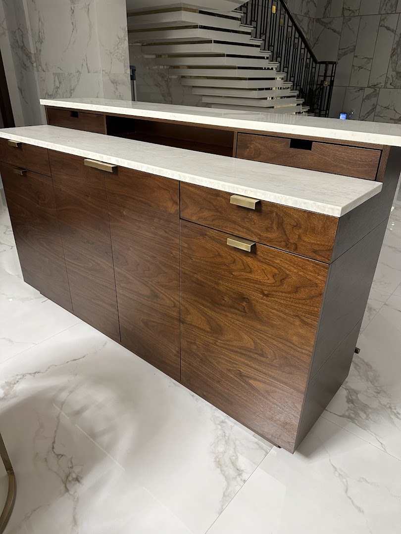 A modern wooden credenza with a white marble top and brass handles.