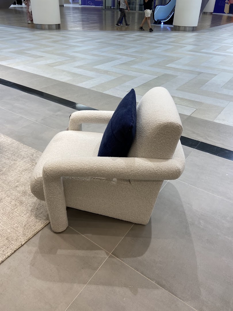 A textured cream armchair with a navy blue cushion sits on a tiled floor.