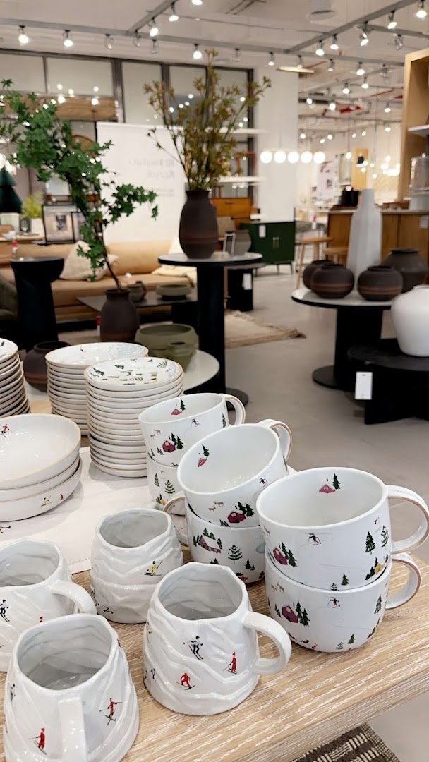 A display of white ceramic mugs and bowls with winter ski-themed designs.