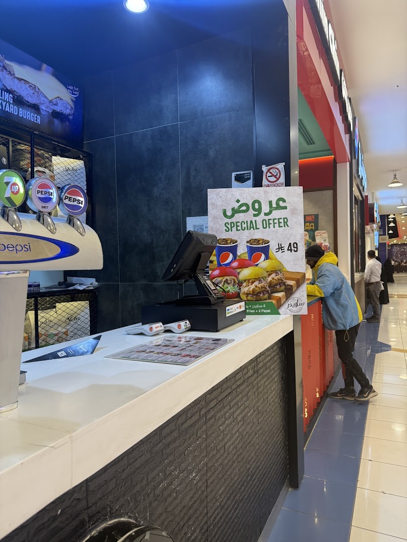 A food counter with a special offer sign featuring burgers, fries, and Pepsi drinks.