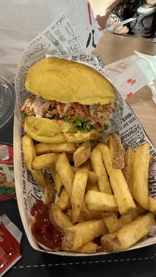 A close-up of a delicious burger and fries from Whataslider, served on branded paper.