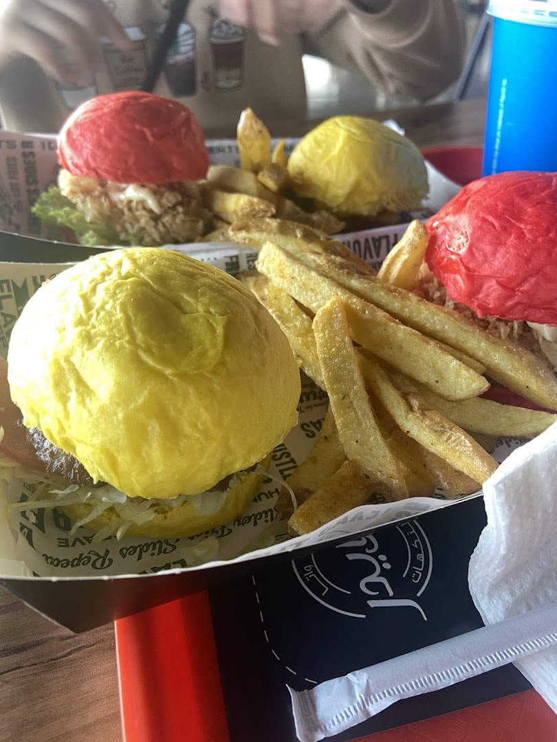 Colorful sliders and french fries served in a tray, with a blue drink in the background.