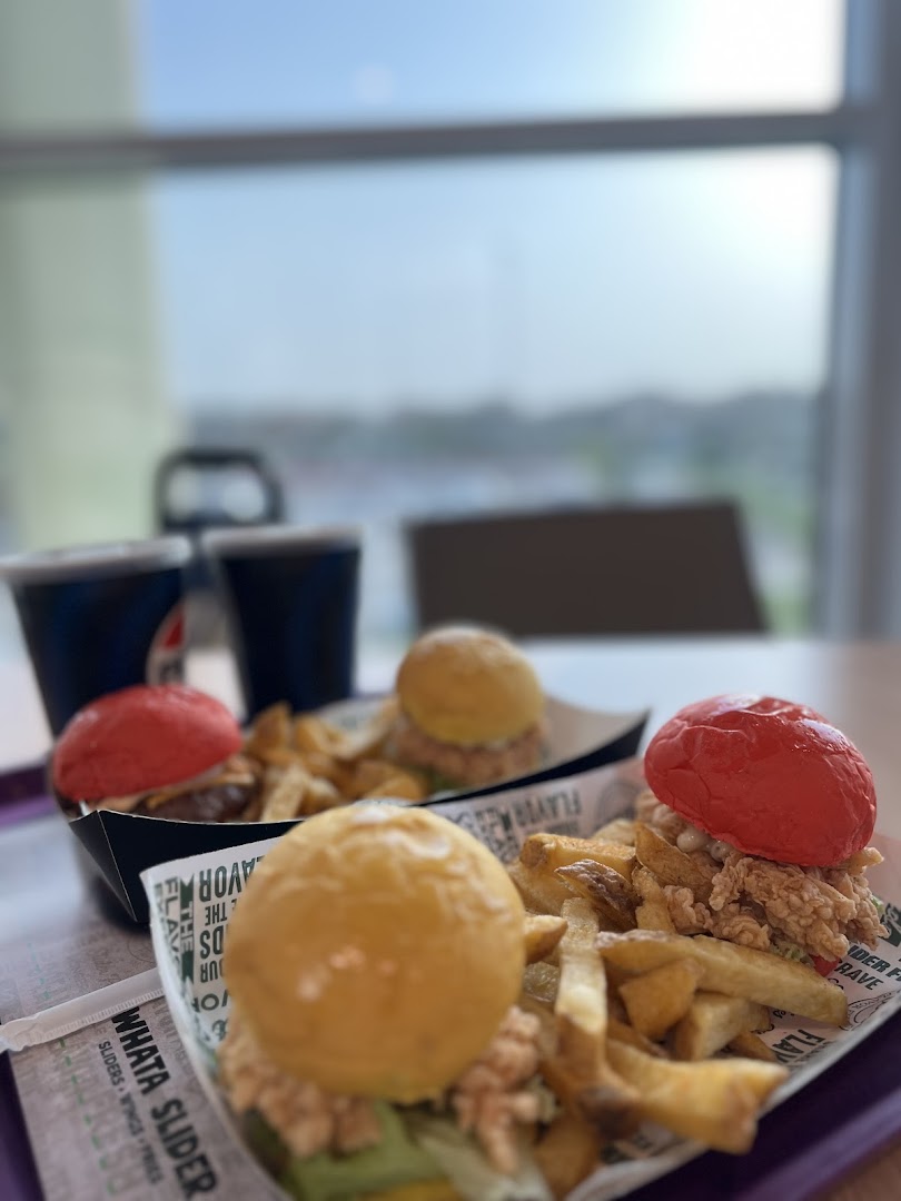A tray of sliders and fries from WhatASlider, with drinks in the background.