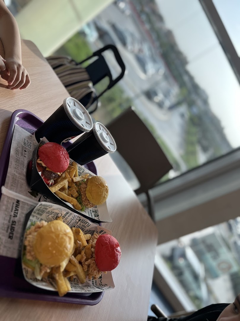 Two colorful sliders with fries and drinks served on trays at WHATASLIDER.