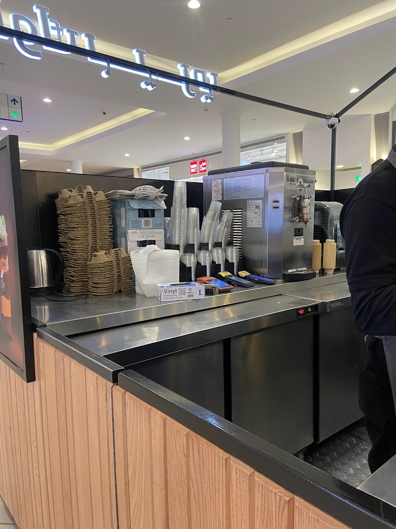 A counter at Oakberry Acai with stacks of cups, a machine, and supplies.