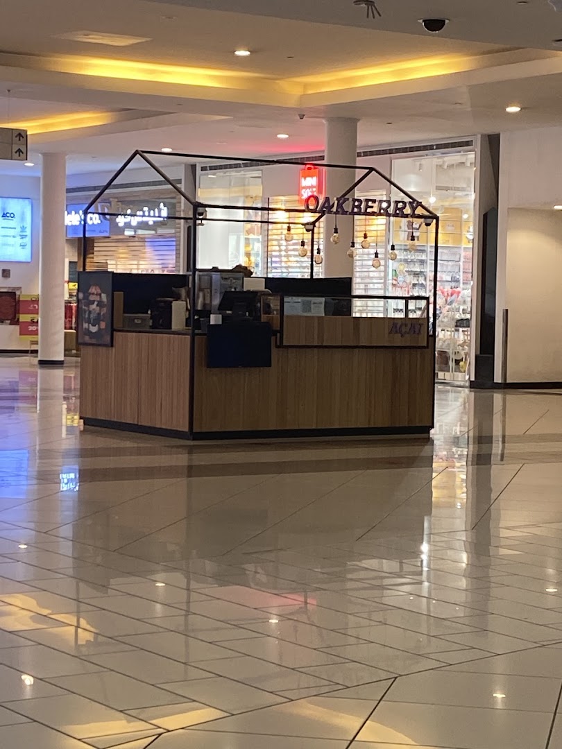 A modern OAKBERRY Acai kiosk with a distinctive house-shaped frame and hanging lights.