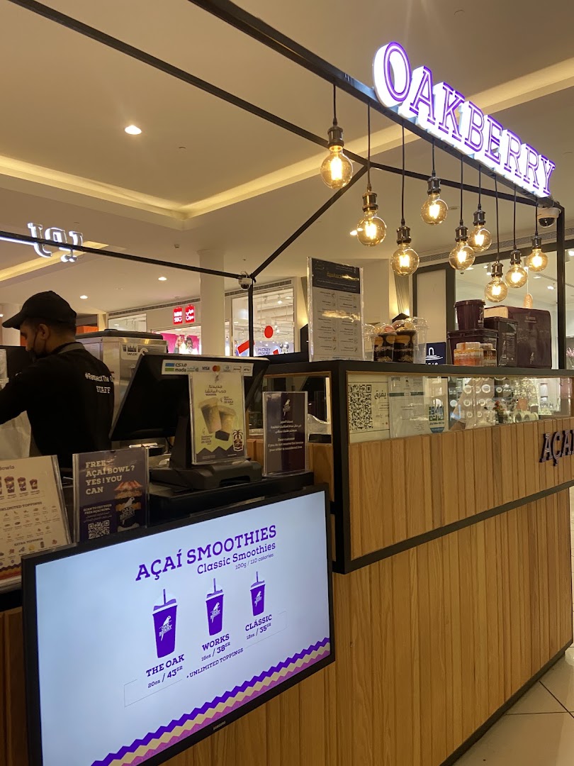 A bright and modern Oakberry Acai shop counter with a digital menu displaying smoothies.