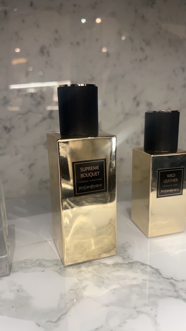 Two luxurious YSL Beauty perfume bottles, one labeled 'Supreme Bouquet' and the other 'Wild Leather'.
