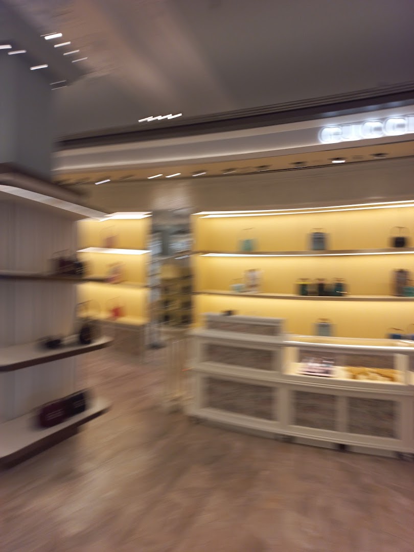 Interior view of a luxury retail store with illuminated shelves displaying handbags.