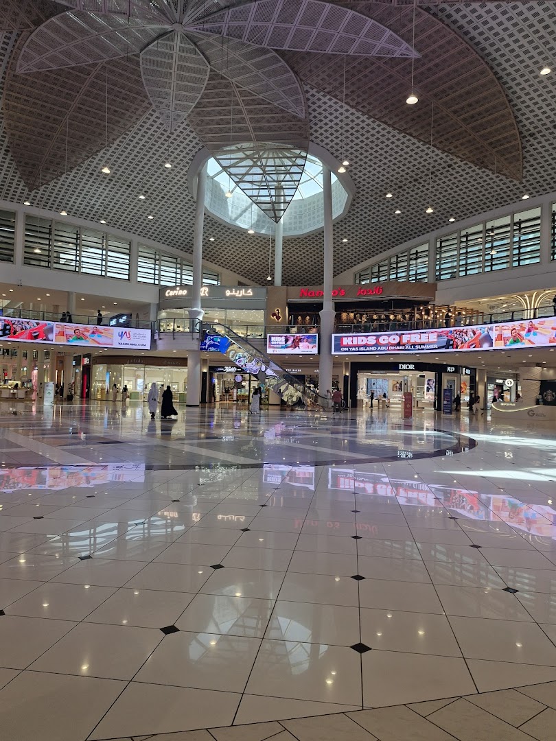Interior view of a modern shopping mall with a high ceiling and various shops visible.