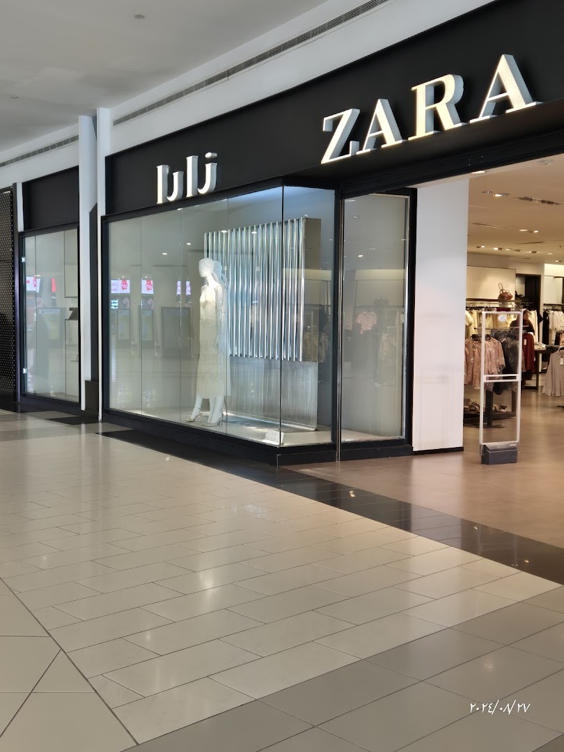 The exterior of a ZARA clothing store with a mannequin in the window display.