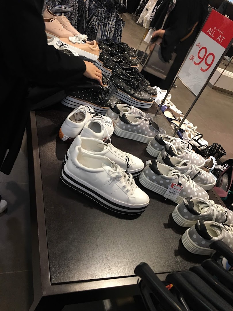 A display of various women's shoes, including sneakers and heels, with a price sign in the background.