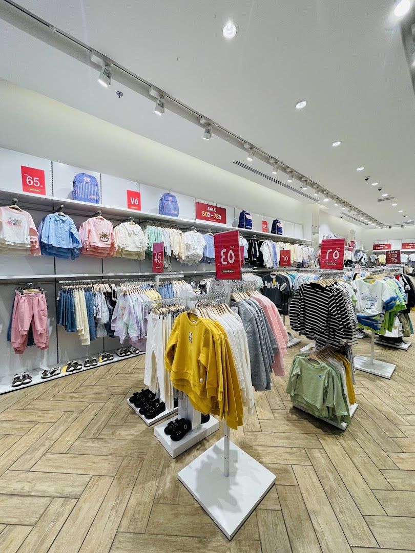 A well-lit retail store interior showcasing children's clothing and accessories on display racks and shelves.