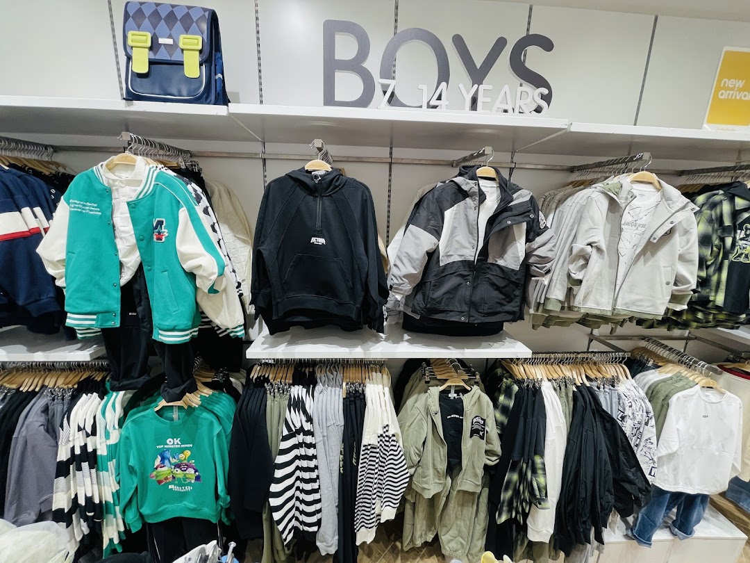 A display of boys' clothing, featuring jackets, hoodies, and sweaters, with a backpack on top.