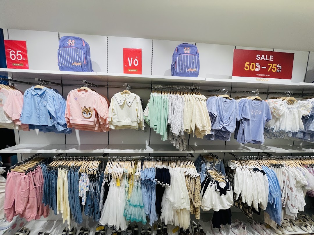 A well-stocked clothing store display featuring children's apparel and backpacks with sale signs.