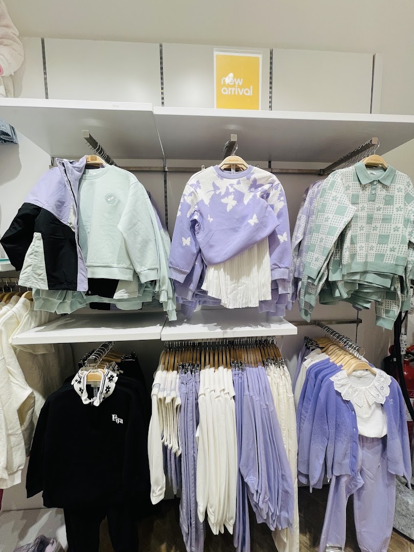 A display of new arrival clothing in pastel colors, featuring sweaters and jackets.