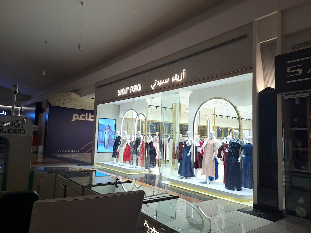 A fashion store with mannequins displaying elegant dresses in a mall setting.